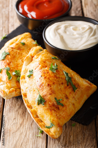 Delicious homemade pizza calzone with sauce close-up on the table. vertical