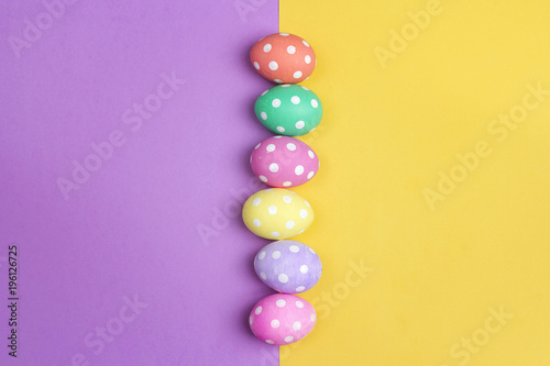 Colored Easter eggs on purple and yellow background. Space for text.