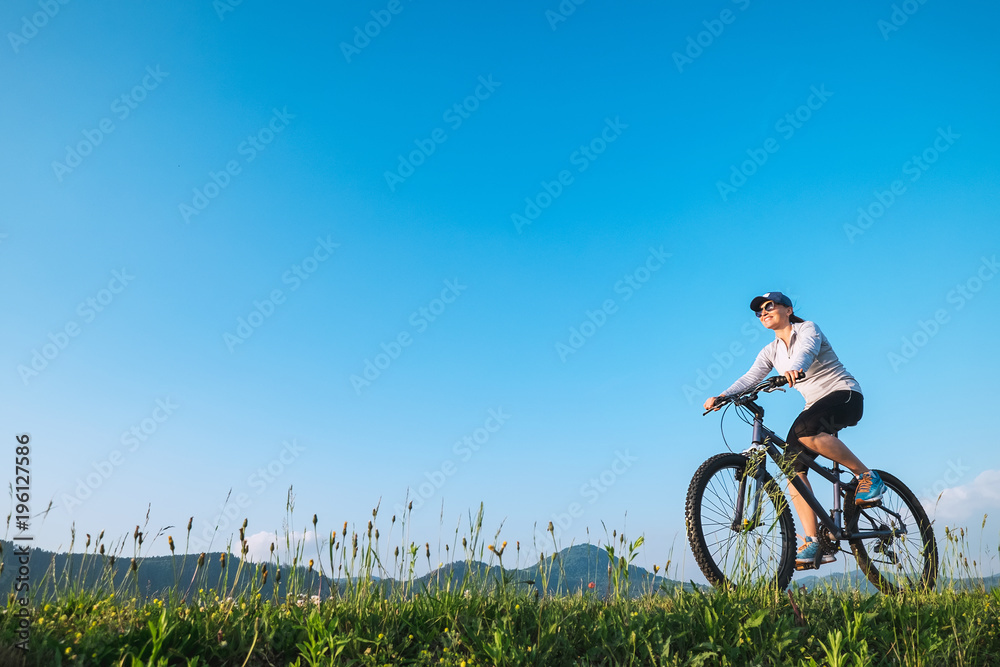 Naklejka premium Woman ride a bike: summertime activity