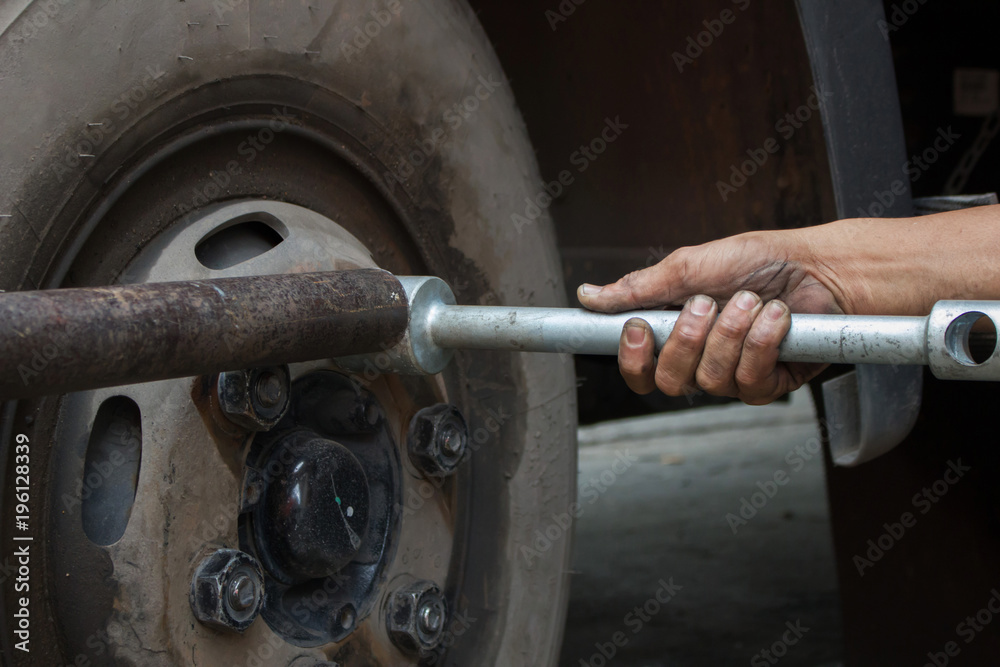 Hand of a man and screwing nut for changing truck tires. Hand of a man and screwing nut for changing truck tires.
