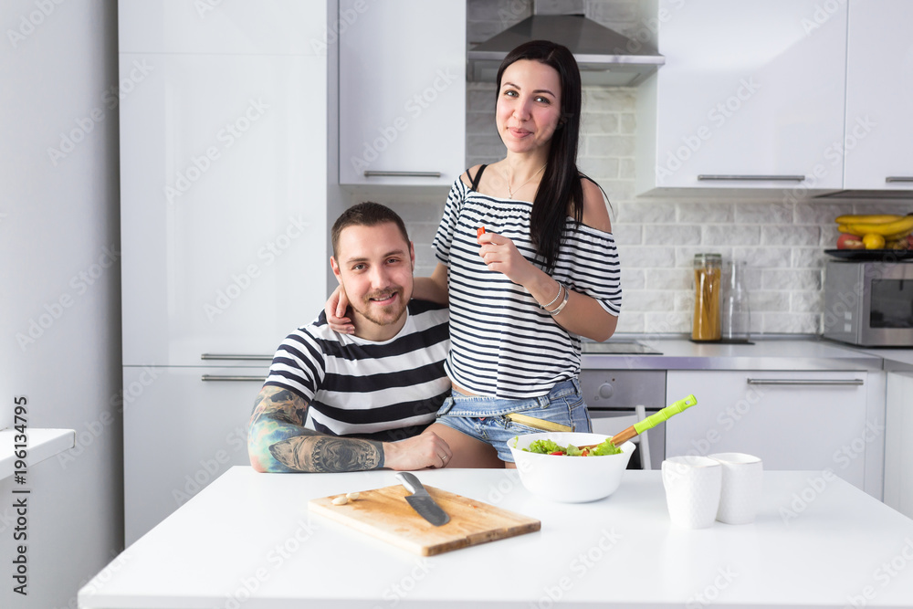 Smiling young couple cooking healthy food in the white home kitchen together Smiling young couple cooking healthy food in the white home kitchen together