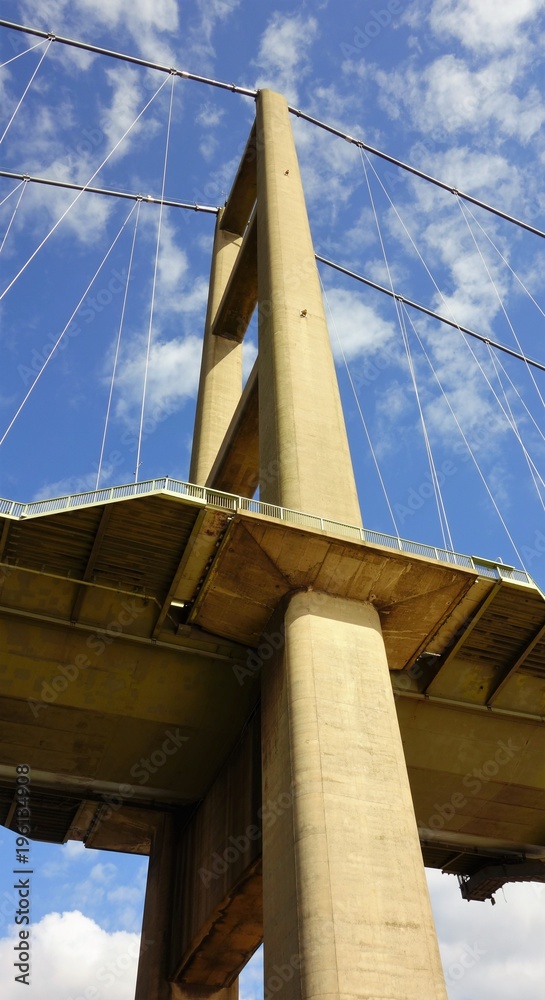 Obraz premium One end of the Humber Bridge looking up from underneath with blue sky and white clouds behind