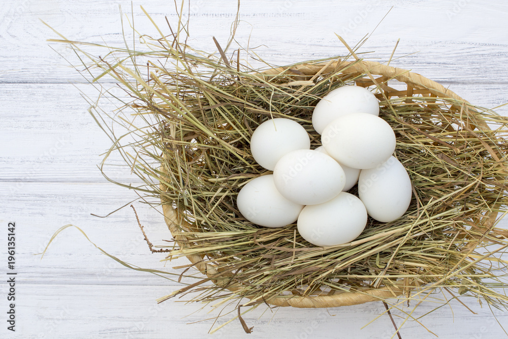 chicken eggs in basket with hay on a white wooden background. eggs on the hay chicken eggs in basket with hay on a white wooden background. eggs on the hay