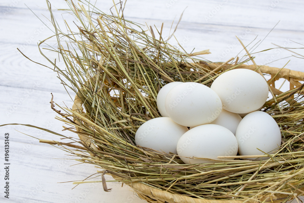 chicken eggs in basket with hay on a white wooden background. eggs on the hay chicken eggs in basket with hay on a white wooden background. eggs on the hay