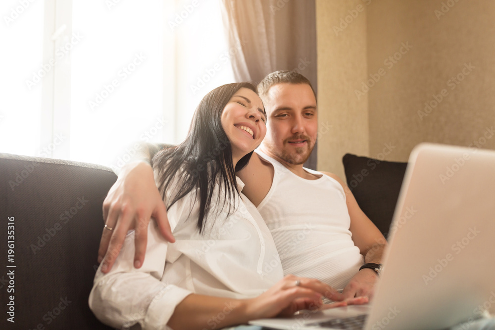 Attractive young couple using a laptop in the living room together Attractive young couple using a laptop in the living room together