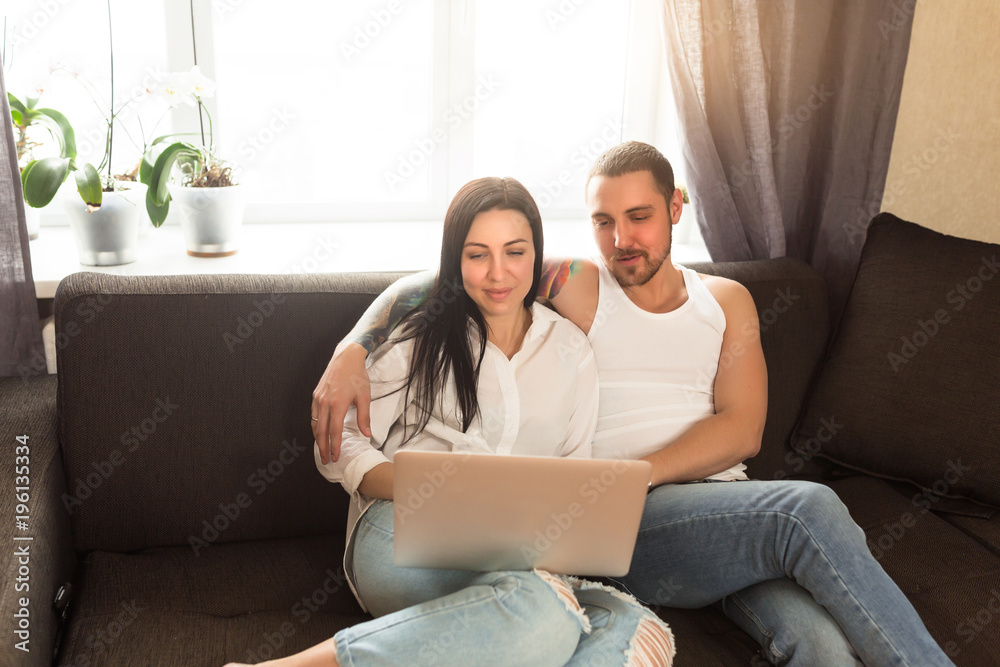 Attractive young couple using a laptop in the living room together Attractive young couple using a laptop in the living room together