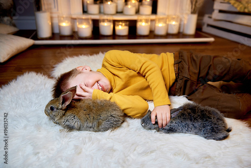Cute little boy playing with funny rabbits at home