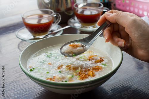Woman eating porridge.Asian female holding spoon with fish eating soft boiled rice for breakfast ,healthy food concept.