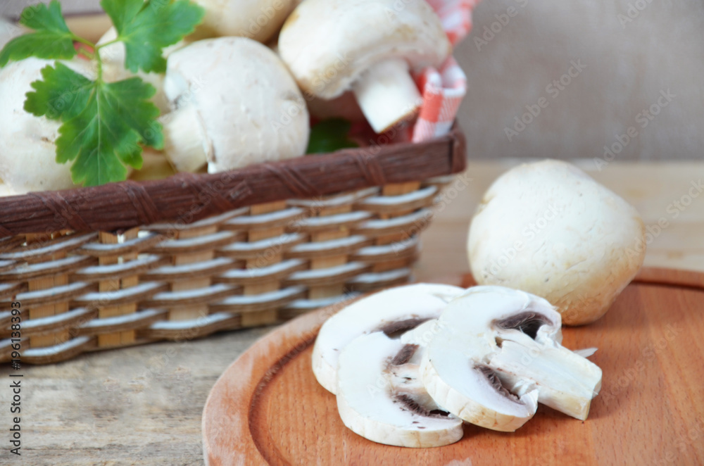 Fresh white mushrooms champignon in brown basket on wooden background. Top view. Copy space