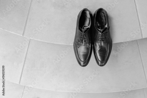 Man shoes on floor close up black color. Expensive shining polished leather male shoes standing at neutral wooden floor background