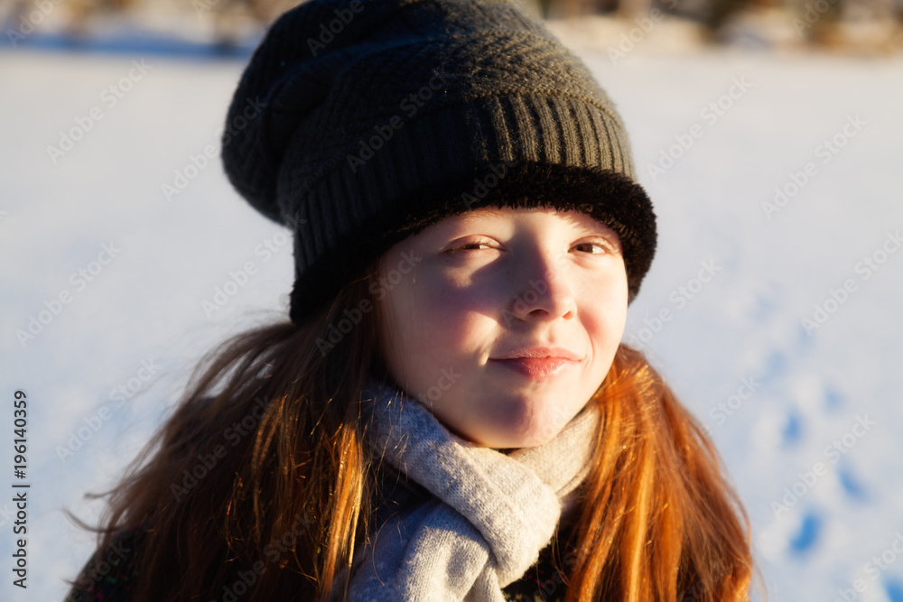 The girl walks in the winter outdoors and smiles