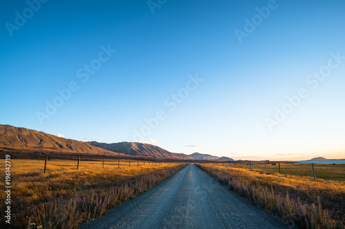 Beautiful scene of the road among the yellow grassland and the mountain beside lake Tekapo.