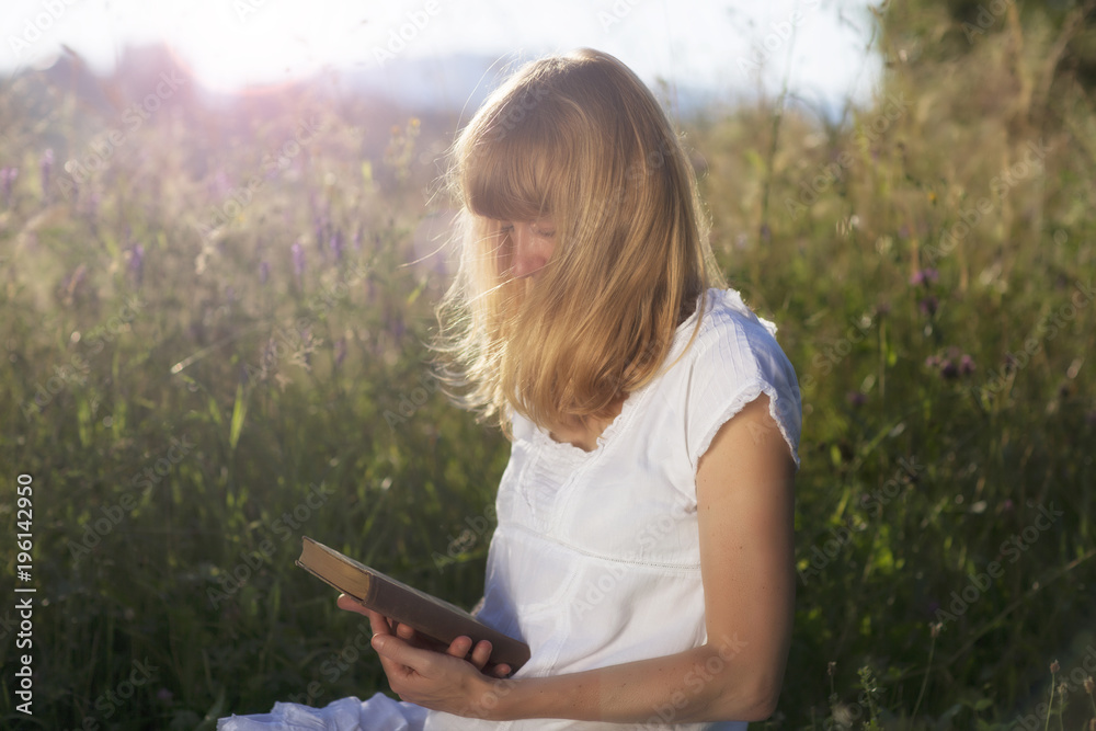 Woman with old book relaxing in the countryside meadow. Selective focus used. Woman with old book relaxing in the countryside meadow. Selective focus used.