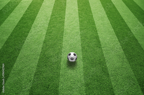 Sunny green football grass field with soccer ball.