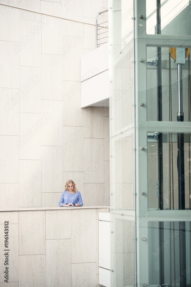 Woman blonde with a digital tablet on a background of modern architecture