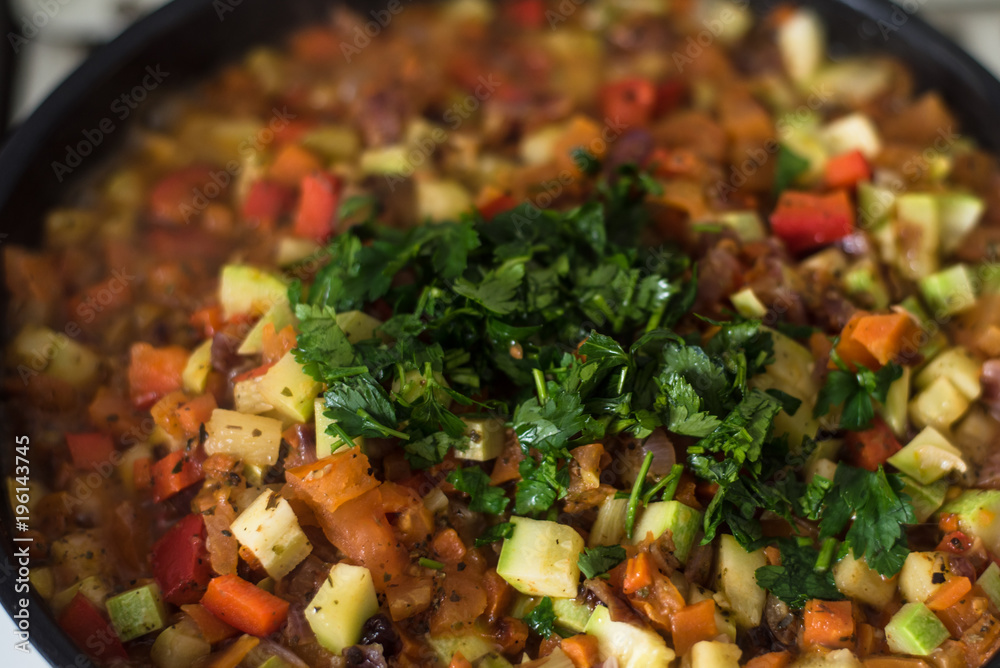 Sliced vegetables are stewed in a frying pan close up - zucchini, pepper, onions, tomatoes Sliced vegetables are stewed in a frying pan close up - zucchini, pepper, onions, tomatoes
