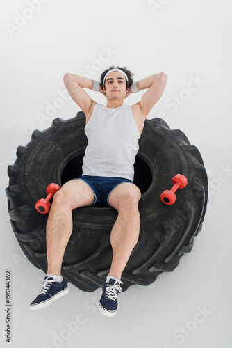 High angle view of thin sportsman resting insde tire of wheel isolated on white photo