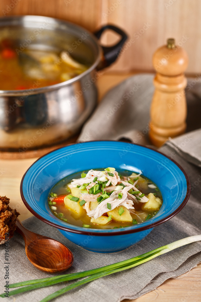 homemade chicken soup with vegetables in blue plate on wooden table. homemade chicken soup with vegetables in blue plate on wooden table.