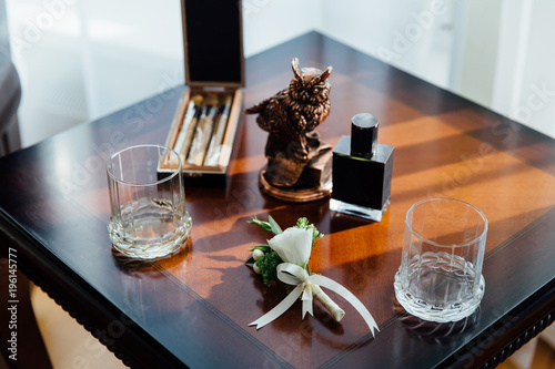 Wedding boutonniere, cigars and alcohol on a wooden table.