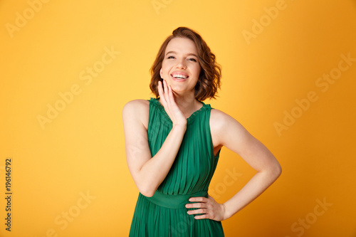 portrait of young smiling woman akimbo isolated on orange