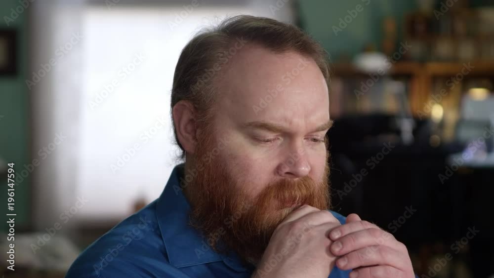 Man looking frustrated as he strokes his beard and rests his head on his hands. Man looking frustrated as he strokes his beard and rests his head on his hands.