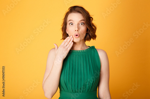 portrait of young surprised woman isolated on orange photo