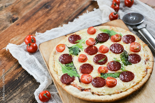 Tasty Pizza With Tomato Sauce, Pepperoni Sausage, And Mushrooms On Wooden Background Natural Rustic, A Pizza Cutter And Ingridienty. photo