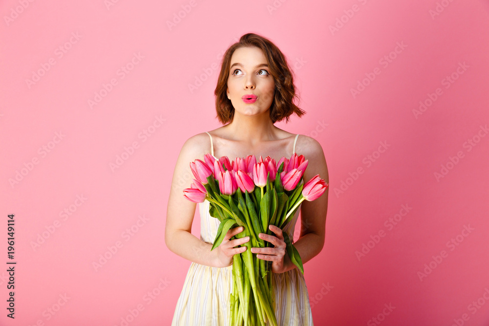 dreamy woman holding bouquet of pink tulips isolated on pink
