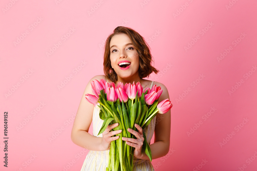 portrait of happy woman holding bouquet of pink spring tulips isolated on pink
