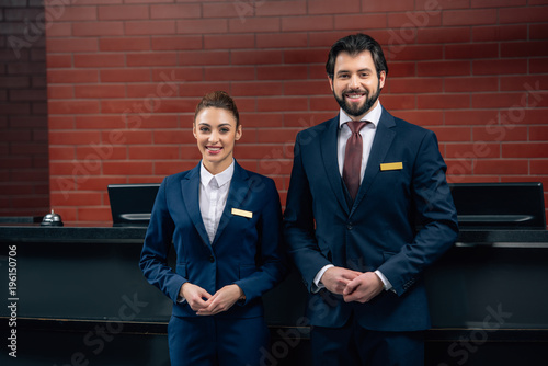 hotel receptionists standing together in front of counter and looking at camera
