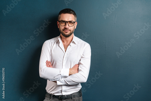 Handsome concentrated man standing over blue background