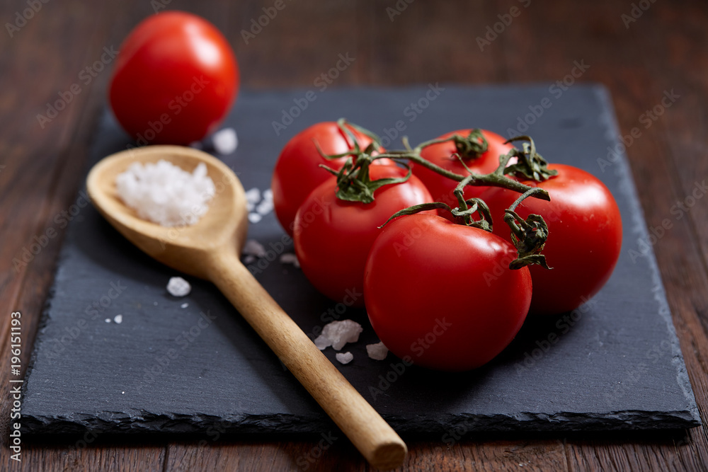 Vegetarian still life with fresh grape tomatoes, pepper and salt in wooden spoon on wooden background, selective focus