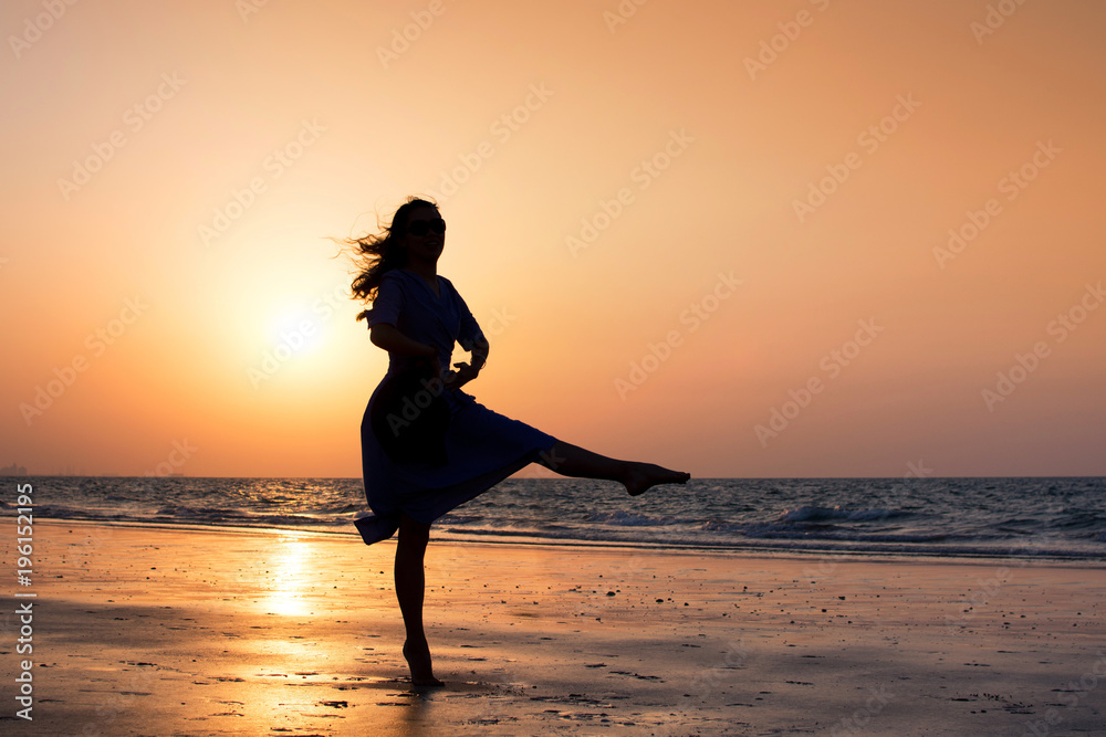 Girl dancing on the beach at sunset