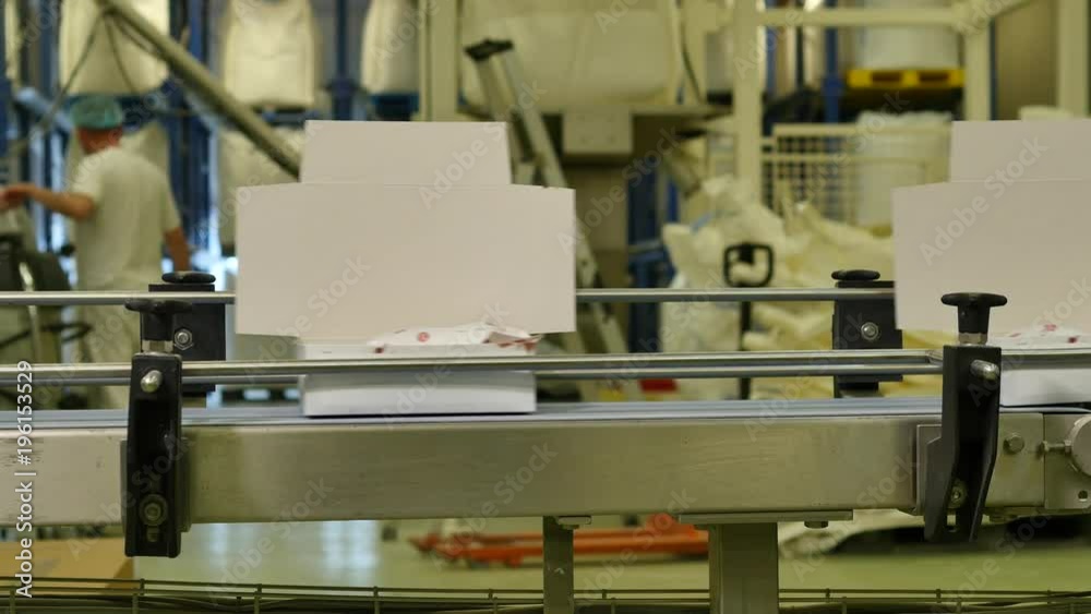 White open unfolded boxes travelling on a conveyor belt in a factory White open unfolded boxes travelling on a conveyor belt in a factory