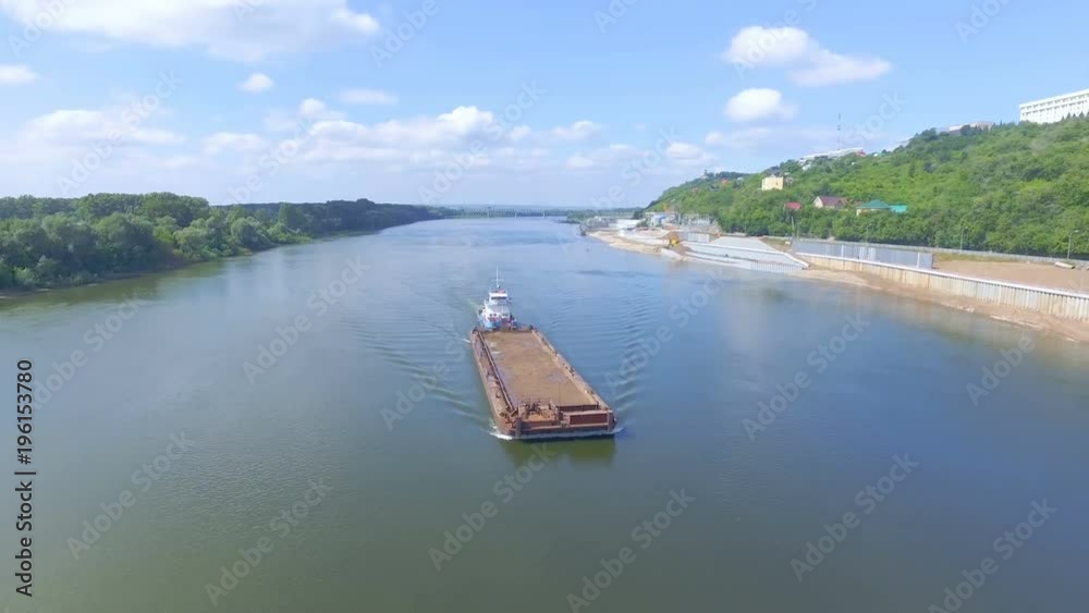 AERIAL: An empty barge floats on the background of works on the construction of the embankment. AERIAL: An empty barge floats on the background of works on the construction of the embankment.