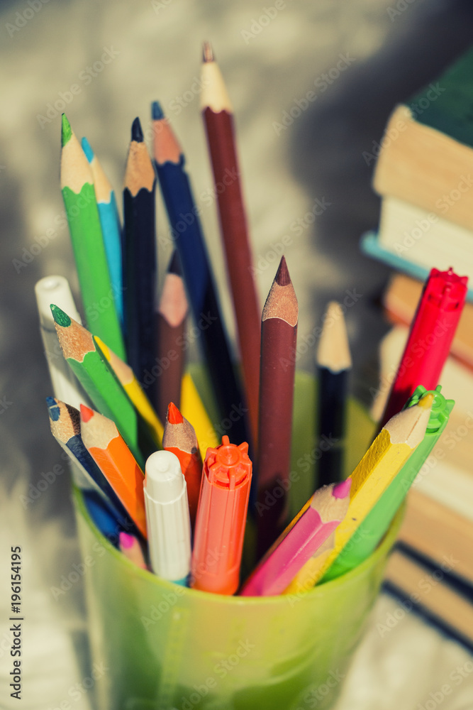 colored pencils in plastic Cup with books colored pencils in plastic Cup with books