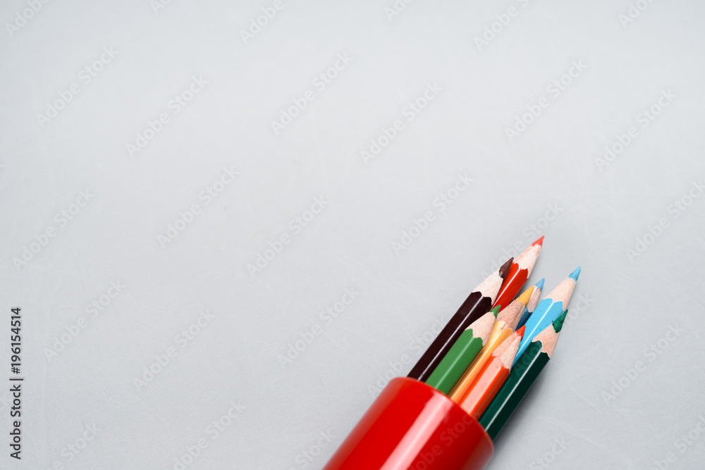 Obraz premium Colored pencils in a red case on white background.