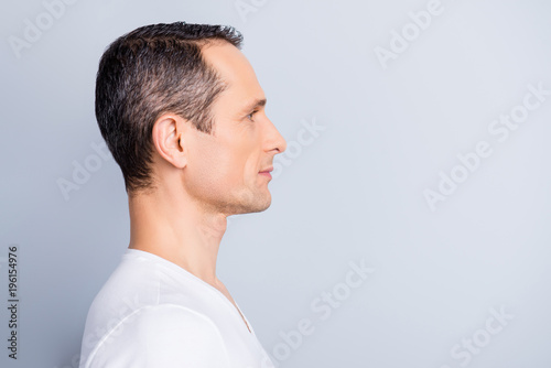 Profile, half face portrait with copy space of trendy, attractive, stylish, man looking at empty place for advertisement, product, having perfect ideal oiled, dry skin, isolated on grey background