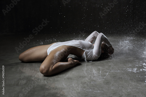 Aqua zone studio shot of sexy fitness young woman with wet blonde hair in white dress lies on the floor