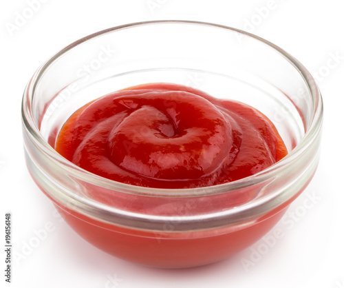 Small glass condiment bowl of red tomato sauce ketchup. Isolated on white