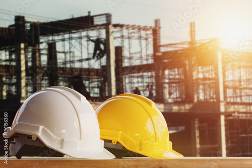 white and yellow safety helmet in construction side with sunset photo