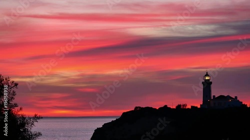 sunset painting the sky in several shades of red with lighthouse silhouette, Carvoeiro, Algarve, Portugal