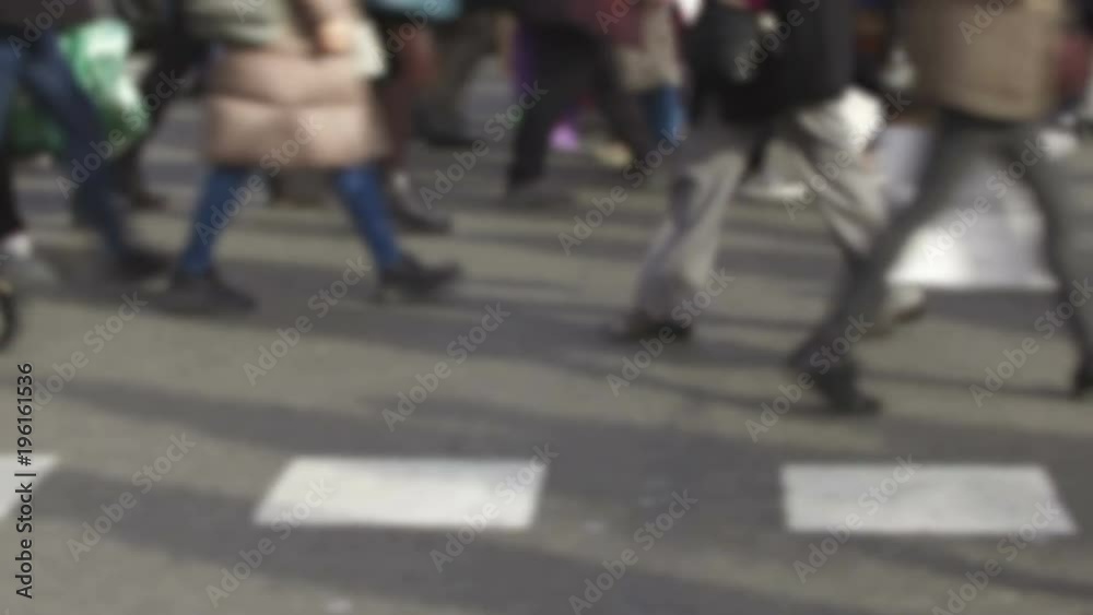 Detail of blurred feet walking toward the left in a pedestrian crossing.Side view feet crossing a street in the city of Barcelona. Smooth camera movement: Tracking Shot left. Detail of blurred feet walking toward the left in a pedestrian crossing.Side view feet crossing a street in the city of Barcelona. Smooth camera movement: Tracking Shot left.