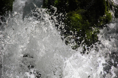 Close up photo of a fresh clean waterfall surrounded by green moss covered rocks