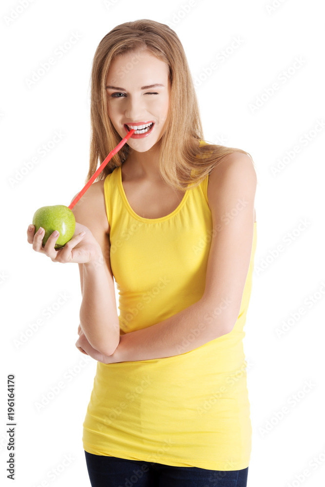 Beautiful caucasian casual slim woman drinking juice from an apple with straw.