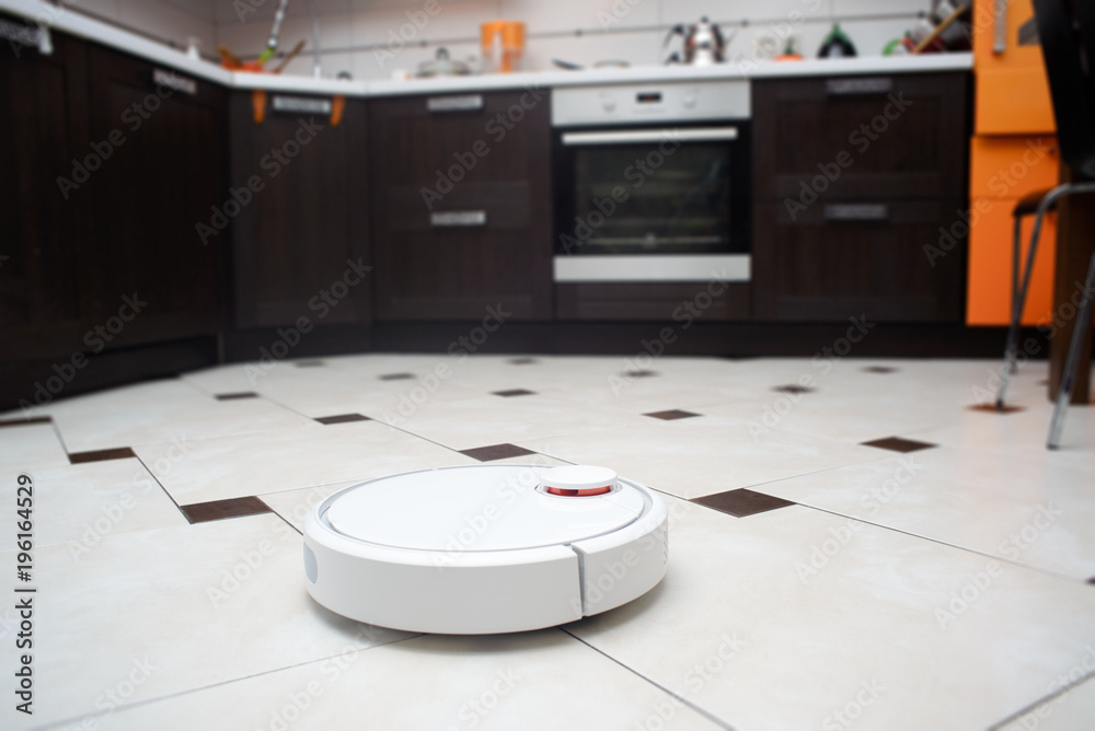 Robotic vacuum cleaner on ceramic tile floor in kitchen. Robotic vacuum cleaner on ceramic tile floor in kitchen.