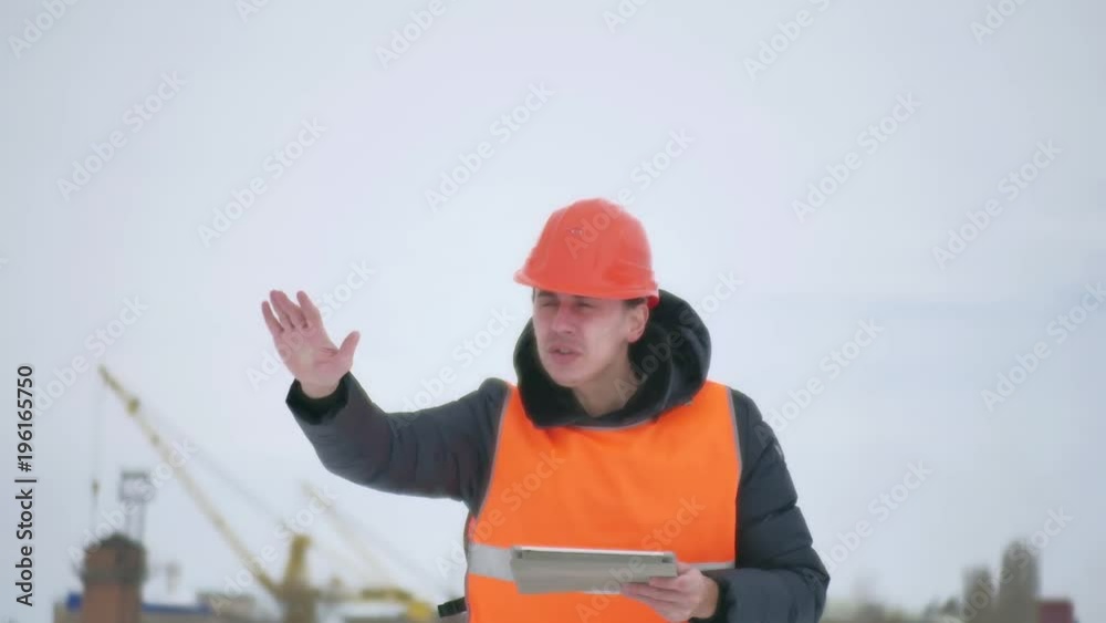 builder foreman waving his arms architect man in helmet with tablet on construction site. construction industry worker in winter building a outdoors house lifestyle builder foreman waving his arms architect man in helmet with tablet on construction site. construction industry worker in winter building a outdoors house lifestyle