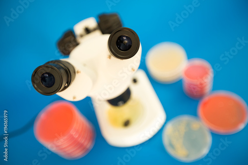 Scientific microscope and petri dishes for scientific research on blue background