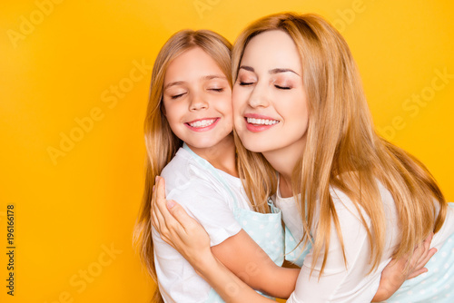 Close up portrait of two people lovely mommy mom mum and cute adorable sweet lovely small daughter wearing white tshirts aprons hugging each other with toothy smile isolated on background copy-space