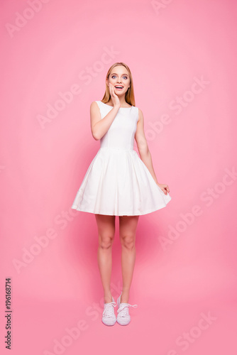 Vertical full-length portrait of sweet charming nice excited cheerful lovely romantic trustful impressed reaction rejoicing girl wearing cocktail dress touching the bottom isolated on background